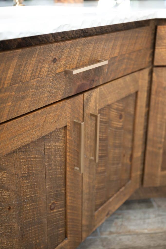 Close-up of rustic wooden custom cabinets with a visible wood grain texture, crafted by a skilled cabinet maker, featuring modern metal handles and a countertop above.